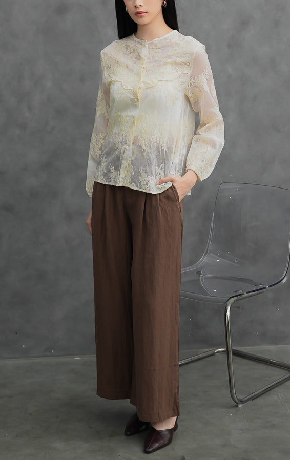 Blus wanita lengan panjang warna krem muda (ivory) Astridia Top berbahan sheer transparan terstruktur dengan detail bordir bunga (floral embroidery) dan bukaan kancing depan.