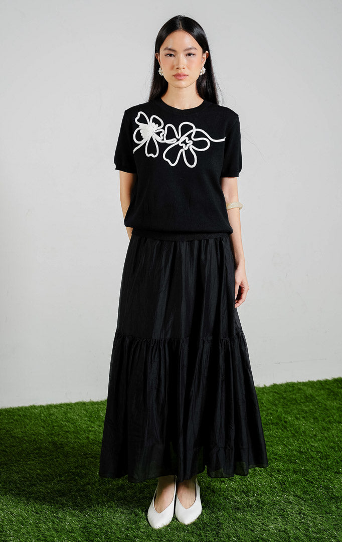 Nadeleine Floral Cord Knit Top warna black, baju atasan rajut lengan pendek wanita warna hitam dengan detail rajutan tali bentuk bunga warna putih dari This Is April.