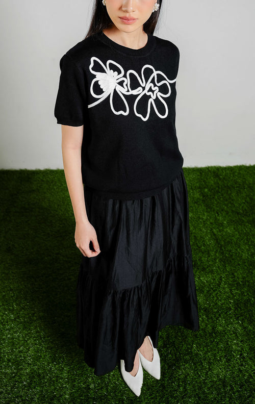 Nadeleine Floral Cord Knit Top warna black, baju atasan rajut lengan pendek wanita warna hitam dengan detail rajutan tali bentuk bunga warna putih dari This Is April.
