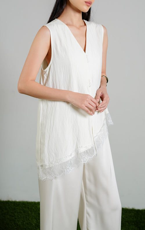 Wynne V-Neck Blouse Top dengan detail Lace Slanted Hem warna ivory, baju atasan tanpa lengan wanita model leher V dan ujung miring berenda warna putih gading dari This Is April. 