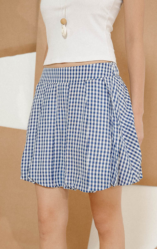 Model berdiri mengenakan Athens Gingham Skort Navy, produk rok celana wanita pendek dengan motif kotak-kotak gingham warna biru navy dipadukan tank top putih. 