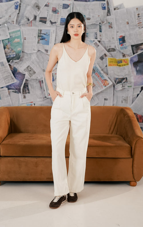 celana panjang denim warna putih (white jeans) dengan potongan lurus dan clean look. Celana memiliki saku depan fungsional dipadukan atasan camisole serta sepatu sneakers untuk gaya kasual modern.