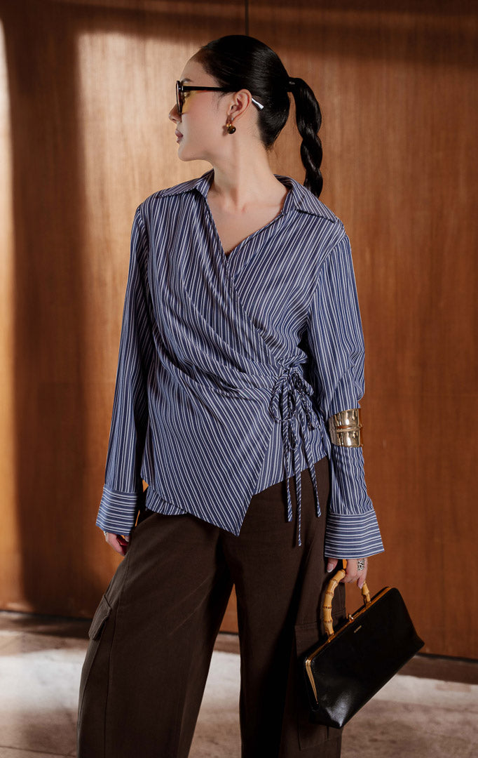 Kemeja wanita lengan panjang motif garis warna navy (navy striped shirt top) Audreyna Top dengan garis leher V yang menawan (flattering V-neckline), detail tali halus (delicate tie detail), serta penutup kancing depan dan tali (front button and tie closure).