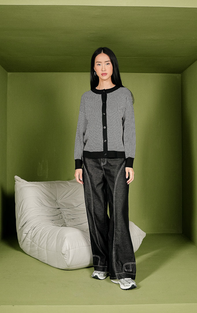Kardigan rajut wanita Avaia Cardigan bermotif hitam putih secara menyeluruh, dilengkapi detail kerah bulat, jalur kancing depan, dan ujung lengan berwarna hitam polos.