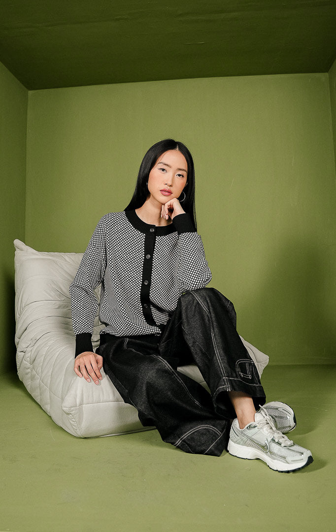Kardigan rajut wanita Avaia Cardigan bermotif hitam putih secara menyeluruh, dilengkapi detail kerah bulat, jalur kancing depan, dan ujung lengan berwarna hitam polos.