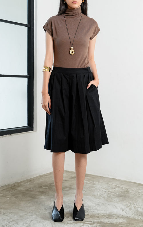 Celana kulot wanita santai warna hitam (black relaxed culotte pants) Avila Pants dengan pinggang bersih (clean waistband), detail lipit di bagian depan (subtle front pleat detailing), dan potongan kaki lebar (wide-leg silhouette).

