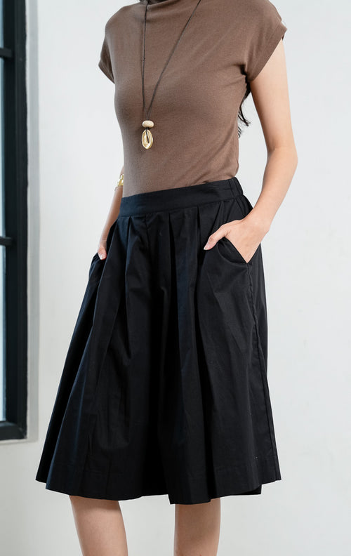 Celana kulot wanita santai warna hitam (black relaxed culotte pants) Avila Pants dengan pinggang bersih (clean waistband), detail lipit di bagian depan (subtle front pleat detailing), dan potongan kaki lebar (wide-leg silhouette).


