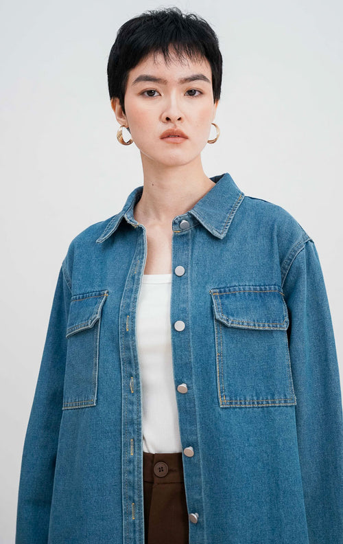 Model mengenakan Ayven Denim Jacket, jaket jeans biru lengan panjang dengan dua saku dada, kancing perak, dan siluet terstruktur yang dipadukan dengan celana cokelat.