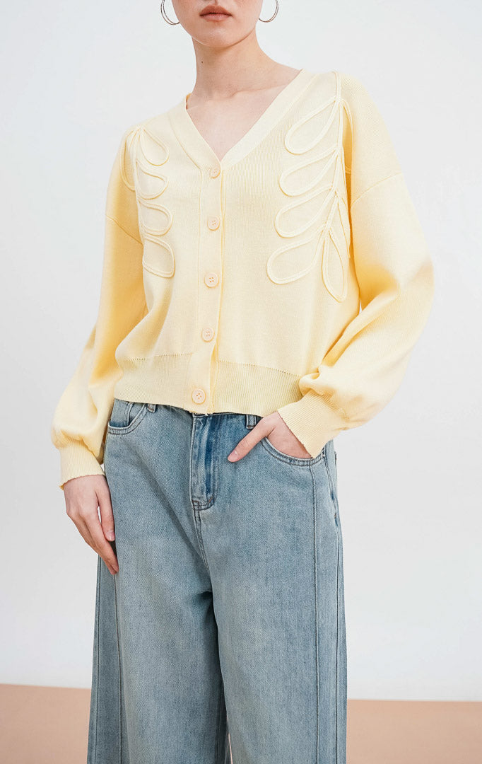 Model mengenakan Bailey Cardigan warna butter yellow, kardigan rajut V neck dengan detail bordir bunga timbul yang elegan dan kancing depan warna senada.