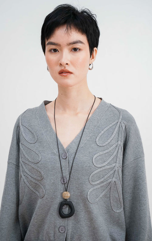 Close up model mengenakan Bailey Cardigan warna grey, kardigan rajut V neck dengan detail bordir bunga timbul yang artistik dan kancing depan warna senada.
