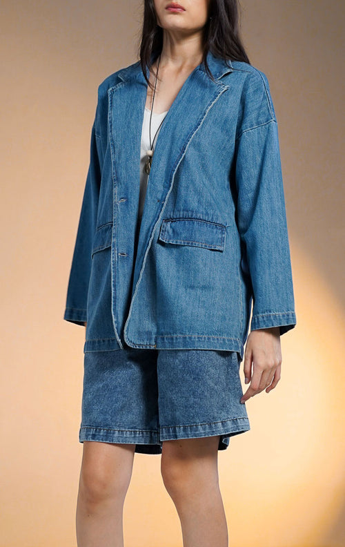 Model wanita mengenakan Barcley Denim Blazer, outer jeans lengan panjang berkerah lapel dengan saku depan dan kancing, gaya kasual modern.