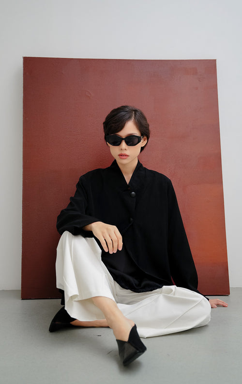 Blazer wanita warna hitam Bernard Blazer dengan model siluet wrap, kerah high shawl, kancing depan tersembunyi (covered button), dan bahu berstruktur.