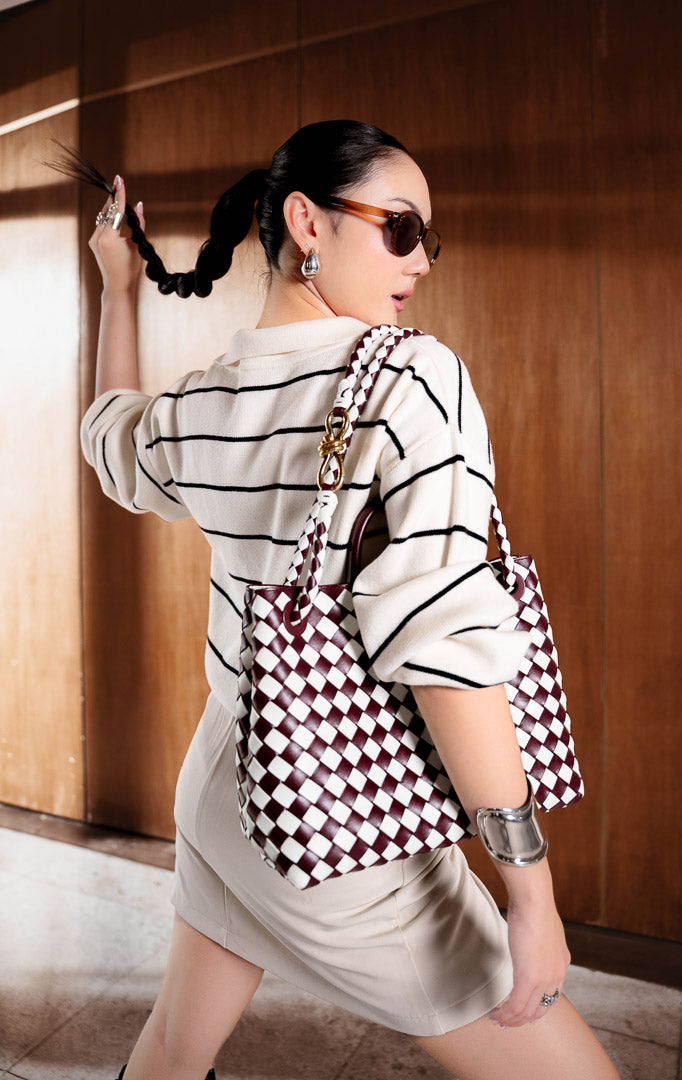 Sweater rajut wanita lengan panjang motif garis warna gading (ivory striped knit sweater) Grifina Sweater dengan siluet longgar santai (relaxed slouchy silhouette), kerah polo V-neck, dan bahan rajut elastis (stretchy knit).