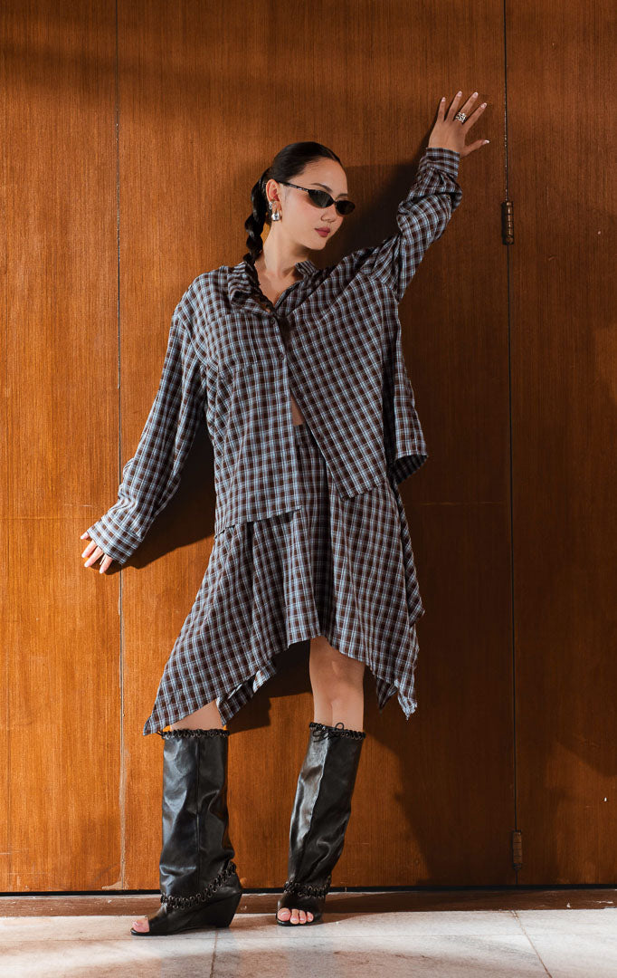 Kemeja wanita lengan panjang motif kotak (brown plaid shirt) Rylanda Top dengan model kerah tegak (band collar), bahan campuran katun poliester berstruktur, detail kancing depan, serta saku fungsional bergaya modern. 