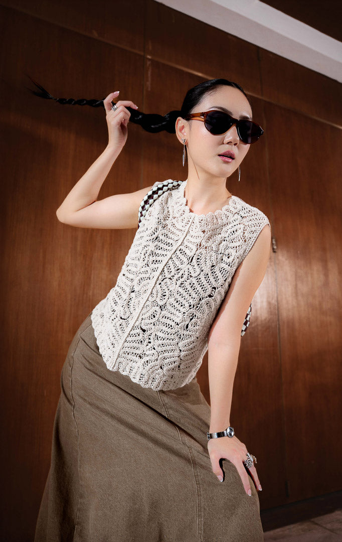 Rompi rajut wanita warna putih gading (ivory heavy crochet vest) Soleria Vest dengan detail pola rajutan crochet artistik yang bertekstur, potongan tanpa lengan, dan kancing belakang bergaya kontemporer.