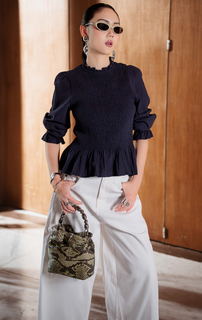 Blouse wanita lengan panjang warna navy (navy long sleeve blouse) Wynfield Top dengan bagian dada smock pas badan (flattering smocked bodice), siluet peplum mengembang lembut (softly flared peplum silhouette), serta bahan campuran katun linen bernapas (breathable cotton-linen blend).