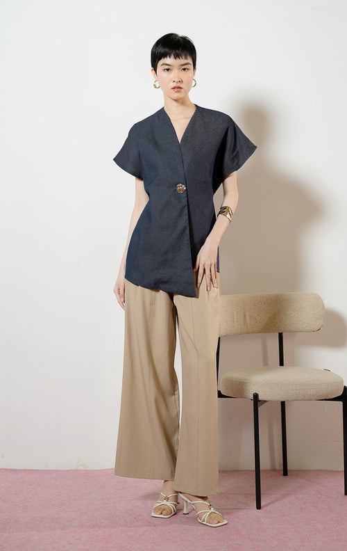 Model wanita mengenakan Loura Minimalist Tailored V-Neck Vest warna navy, atasan blouse wanita lengan pendek berwarna biru dongker dengan potongan asimetris dan kancing logam dekoratif. 