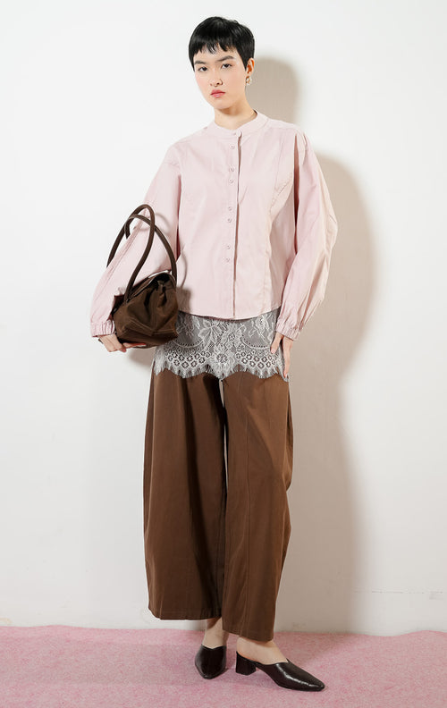 Model wanita mengenakan Rosemarie Round-Neck Twin Button Top warna light pink, atasan blouse kemeja wanita lengan balon warna merah muda dengan detail kancing ganda depan. 