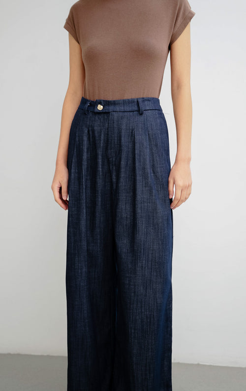 Celana panjang wanita warna biru navy Brielle Pants dengan potongan lurus (straight-cut), bahan katun slub bertekstur, dan aksen kancing emas di bagian depan.