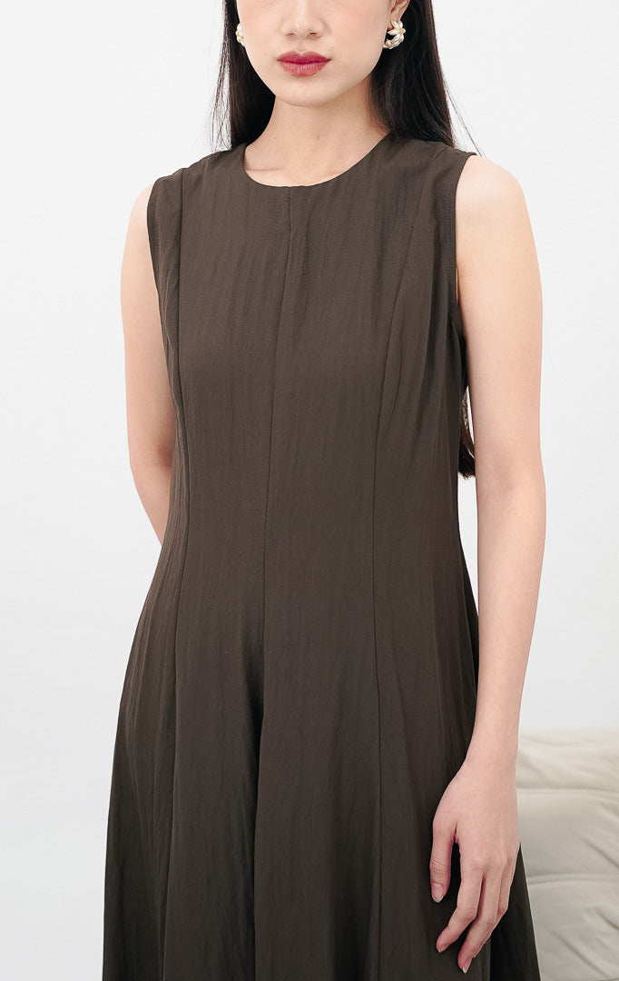 Model wanita mengenakan Callan Dress warna dark brown, gaun maxi tanpa lengan (sleeveless) dengan siluet minimalis dan potongan kerah bulat yang elegan.