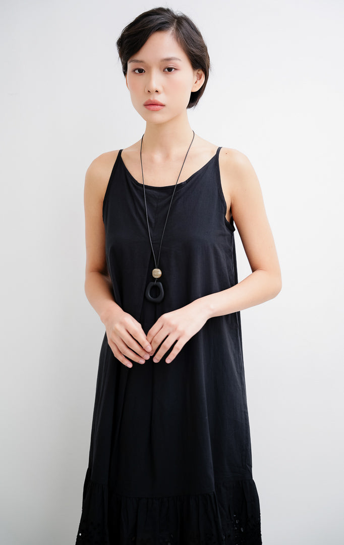 Dress midi wanita tanpa lengan (sleeveless) warna hitam Callia Dress berbahan katun adem dengan aksen bordir broderie cantik di bagian bawah hem.
