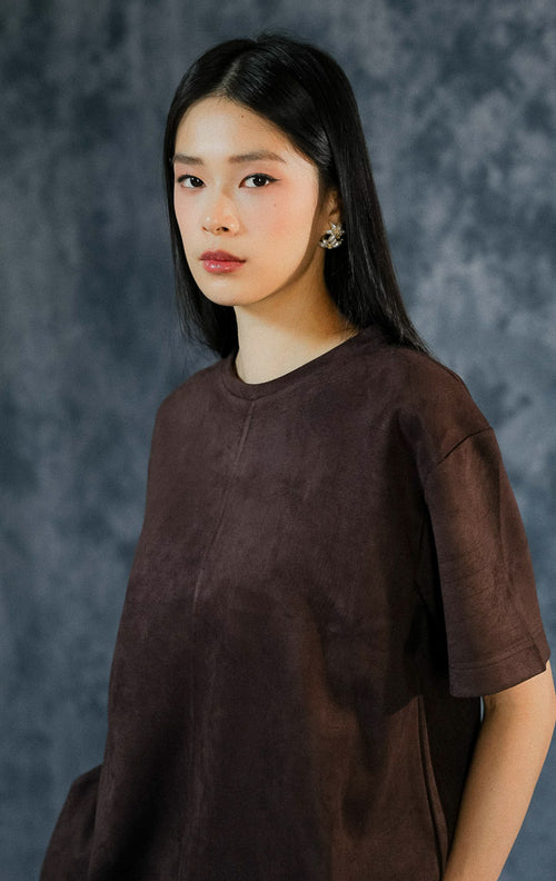 Atasan kasual wanita Callidora warna dark brown dengan siluet longgar (oversized), kerah bulat, dan detail aksen jahitan timbul di bagian tengah depan.