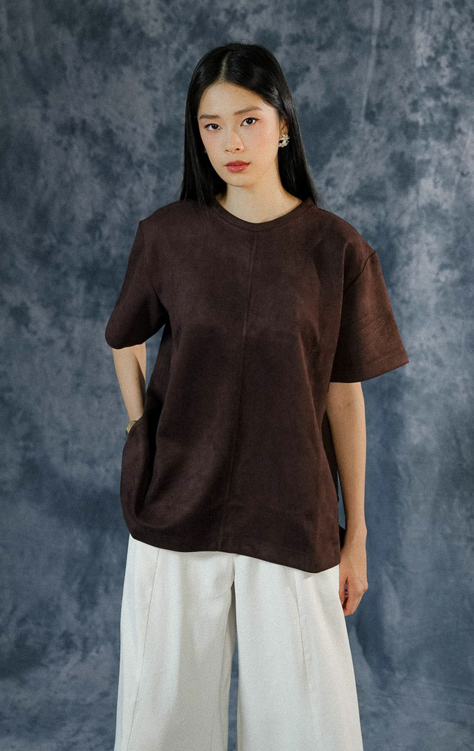 Atasan kasual wanita Callidora warna dark brown dengan siluet longgar (oversized), kerah bulat, dan detail aksen jahitan timbul di bagian tengah depan.
