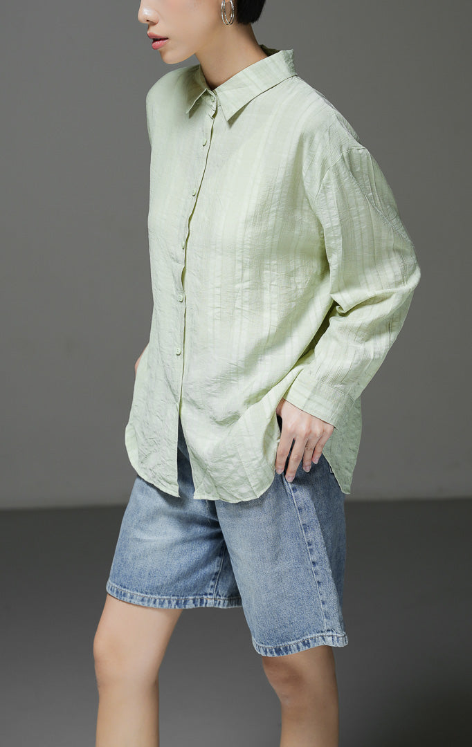 Kemeja wanita Calliope Top warna hijau lengan panjang dengan motif garis tekstur (textured stripe), kerah kemeja, dan kancing depan. 