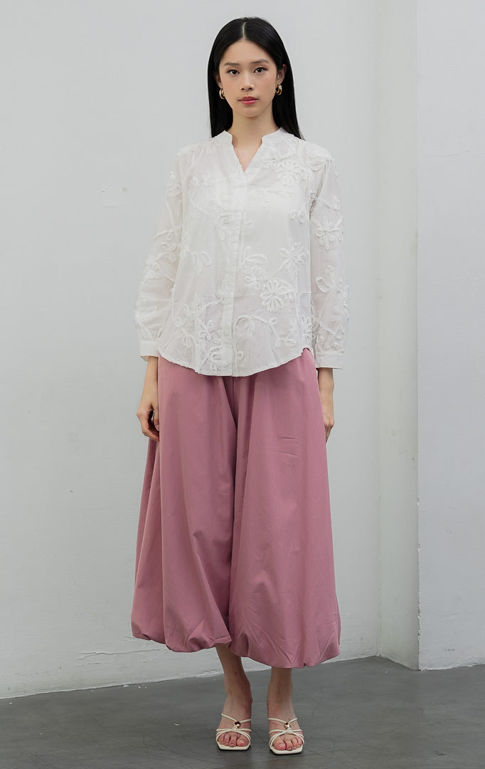 Blus wanita lengan panjang warna putih (white) Camilla Top berbahan katun ringan (lightweight cotton) dengan aksen aplikasi bordir bunga (floral appliqué detailing), efek semi-transparan (subtle sheer), dan bukaan kancing depan.