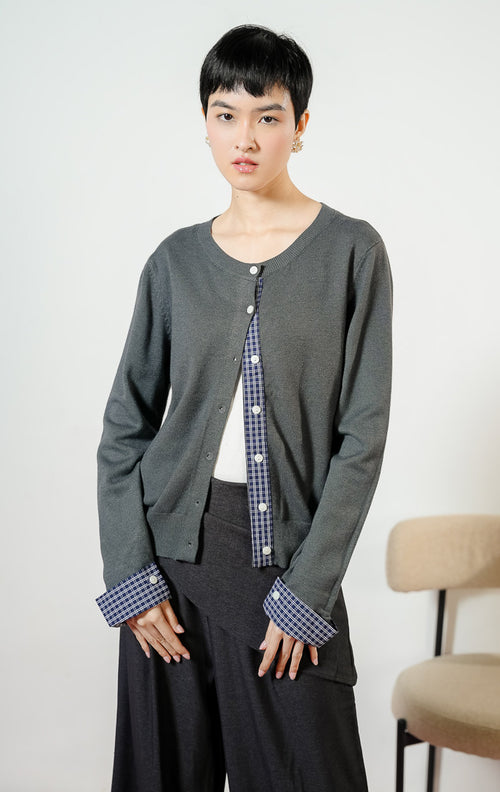 Model wanita mengenakan Kezia Flannel Sleeve Knit Cardigan warna grey, outer cardigan rajut wanita lengan panjang warna abu-abu dengan variasi aksen kain kotak-kotak flanel unik. 