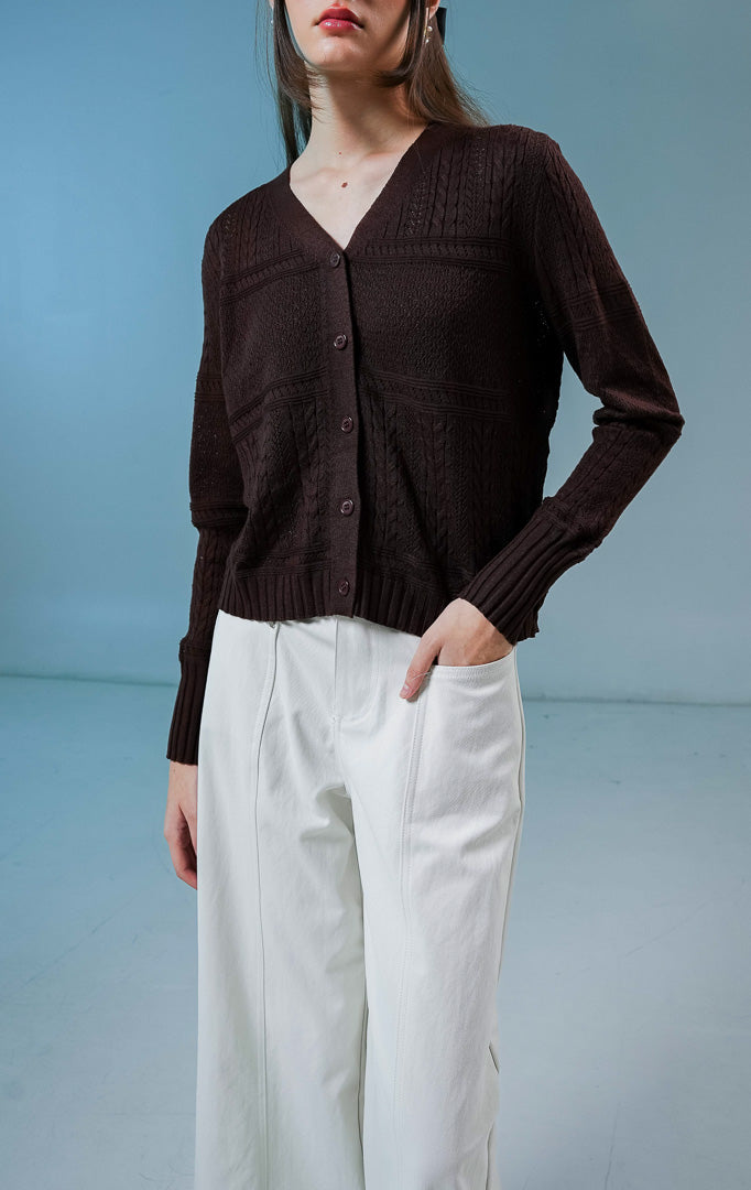 Model wanita mengenakan Wilder Cable Knit Pointelle Cardigan warna dark brown, luaran cardigan rajut wanita leher V-neck berwarna coklat tua dengan perpaduan motif rajut kepang dan lubang mikro anggun. 