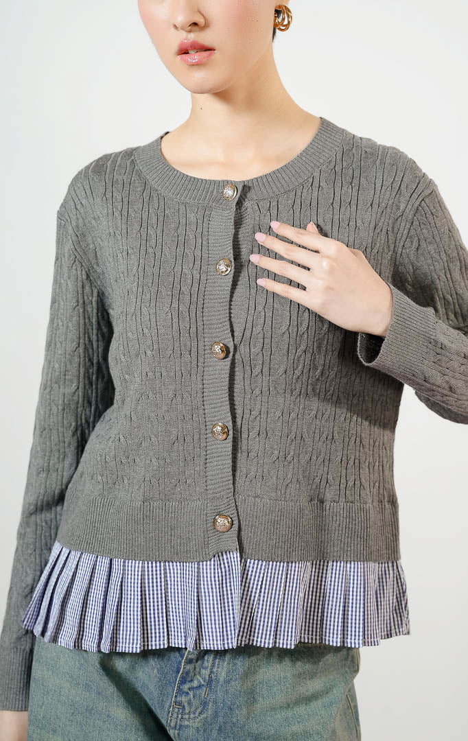Model wanita mengenakan Malora Ruffled Flannel Hem Braided Knit Cardigan warna grey, outer cardigan rajut wanita motif kepang warna abu-abu dengan variasi kelim lipit kotak-kotak gingham biru dan kancing emas. 