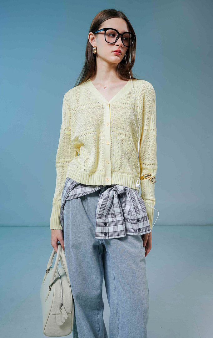 Model wanita mengenakan Wilder Cable Knit Pointelle Cardigan warna butter yellow, luaran cardigan rajut wanita leher V-neck berwarna kuning muda dengan perpaduan motif rajut kepang dan lubang mikro anggun. 