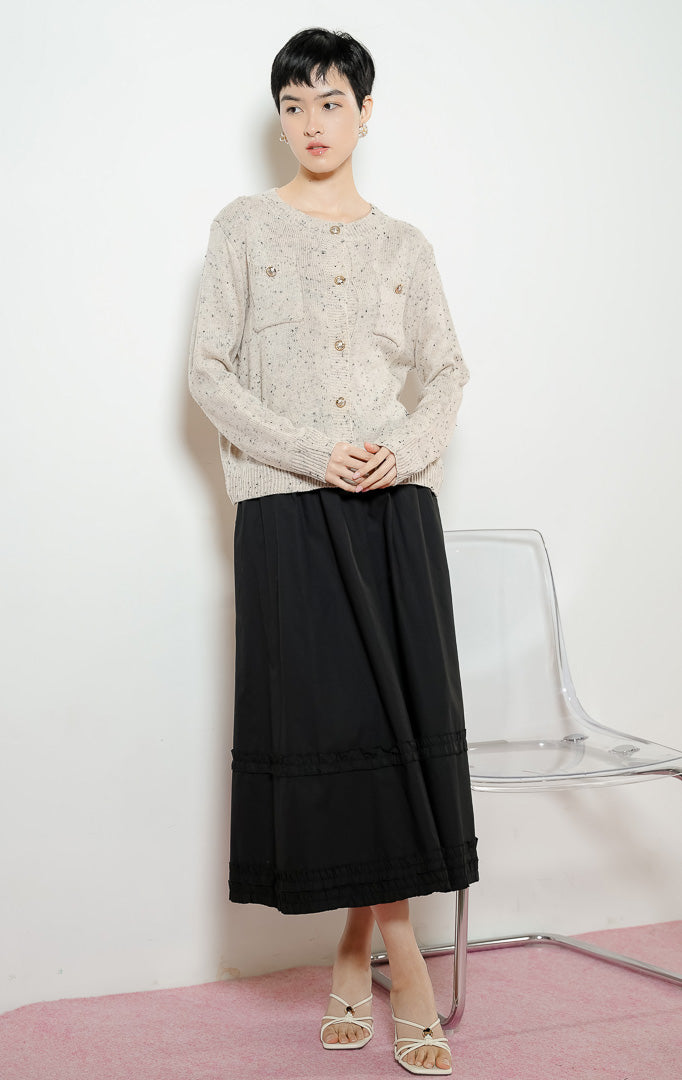 Model wanita mengenakan Chrystelle Gold Button Tweed Knit Cardigan warna ivory, luaran kemeja cardigan rajut wanita bertekstur tweed warna krem dengan kancing emas mewah dan dua saku depan. 