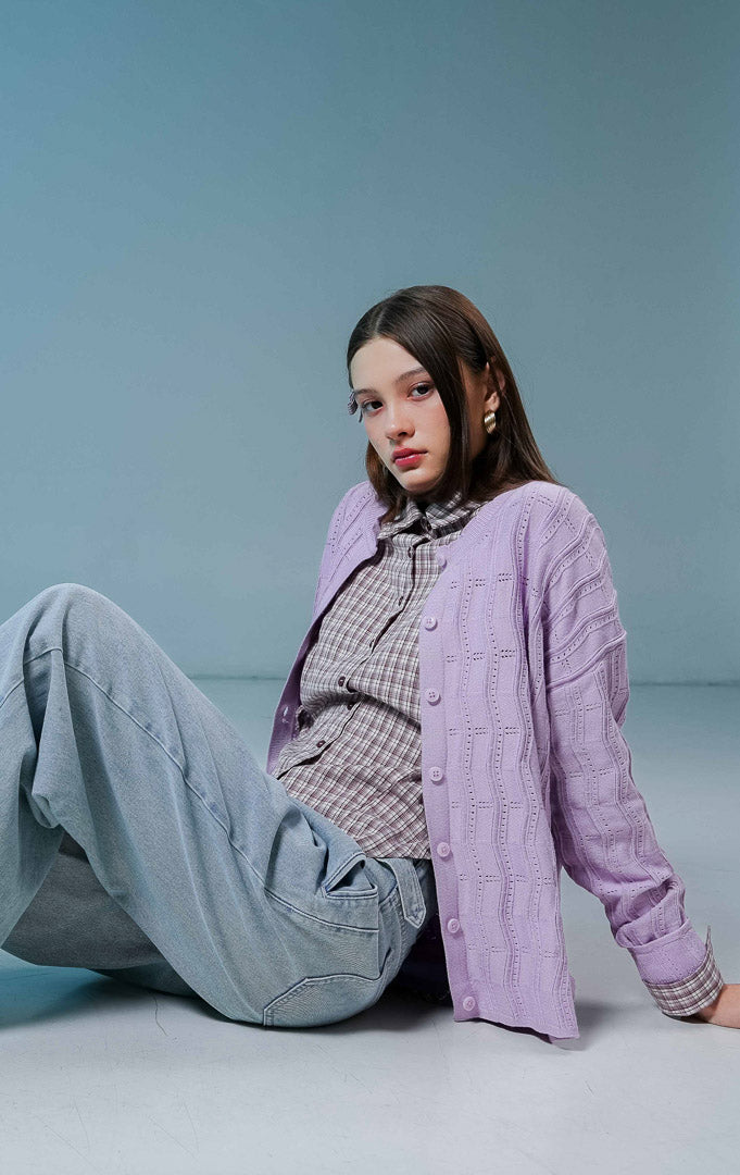 Model wanita mengenakan Twyla Textured Crew Neck Button-Up Cardigan warna purple, luaran cardigan rajut wanita lengan panjang berwarna ungu muda/lilac dengan tekstur vertikal dan kancing depan. 