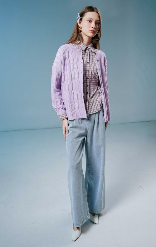 Model wanita mengenakan Twyla Textured Crew Neck Button-Up Cardigan warna purple, luaran cardigan rajut wanita lengan panjang berwarna ungu muda/lilac dengan tekstur vertikal dan kancing depan. 