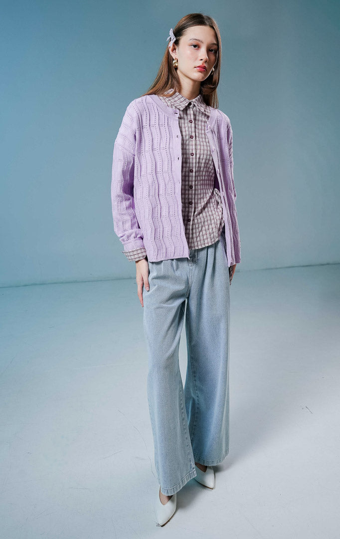 Model wanita mengenakan Twyla Textured Crew Neck Button-Up Cardigan warna purple, luaran cardigan rajut wanita lengan panjang berwarna ungu muda/lilac dengan tekstur vertikal dan kancing depan. 