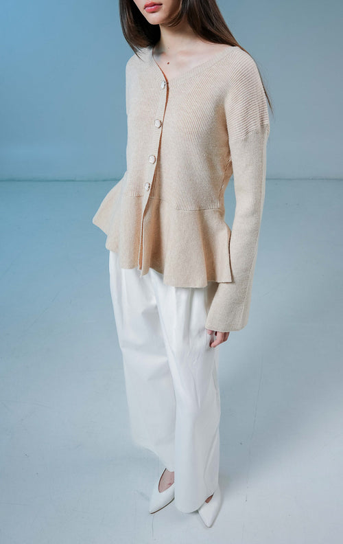 Model wanita mengenakan Eulalie Ribbed Peplum Knit Cardigan warna khaki, luaran rajut wanita lengan panjang bertekstur rib dengan detail kancing depan dan siluet peplum yang feminin. 
