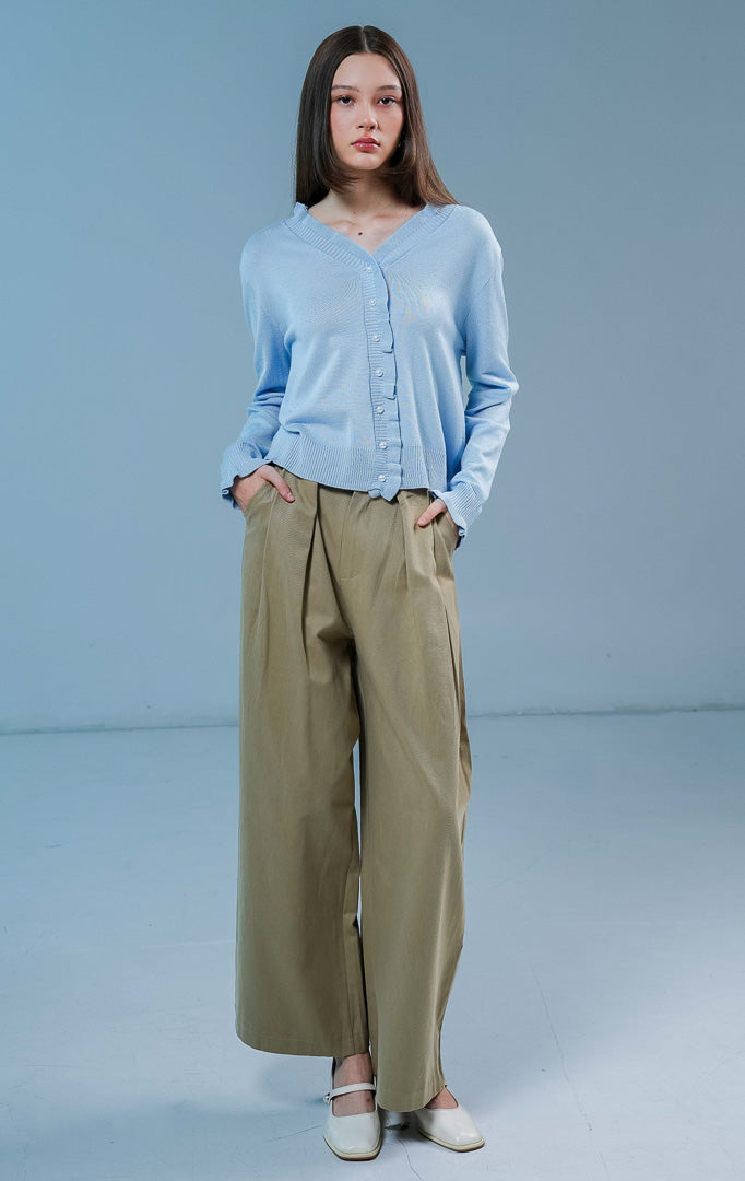 Model wanita mengenakan Graciella Ruffle Knit Cardigan warna light blue, luaran rajut wanita berkerah V dengan detail kerutan (ruffles) yang feminin dan kancing mutiara depan 