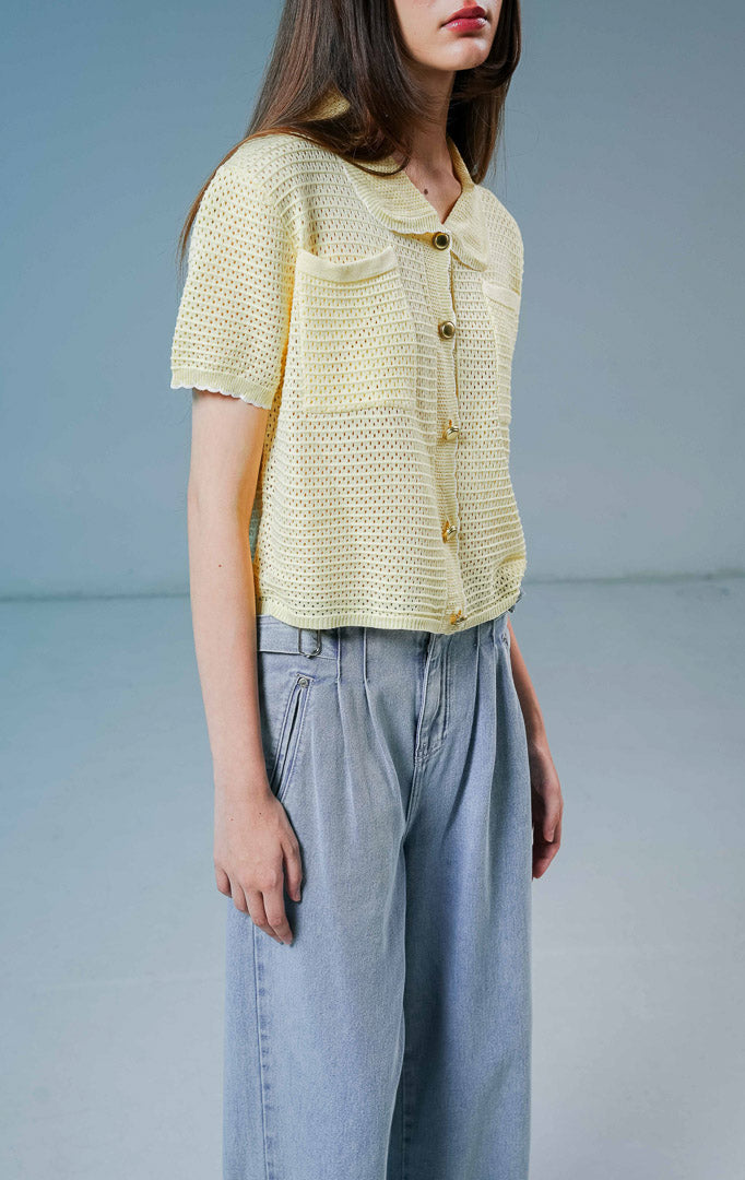 Model wanita mengenakan Mylah Pockets Knit Cardigan warna yellow, luaran cardigan rajut wanita lengan pendek berwarna kuning muda dengan detail kerah bulat, dua saku depan, dan kancing emas. 