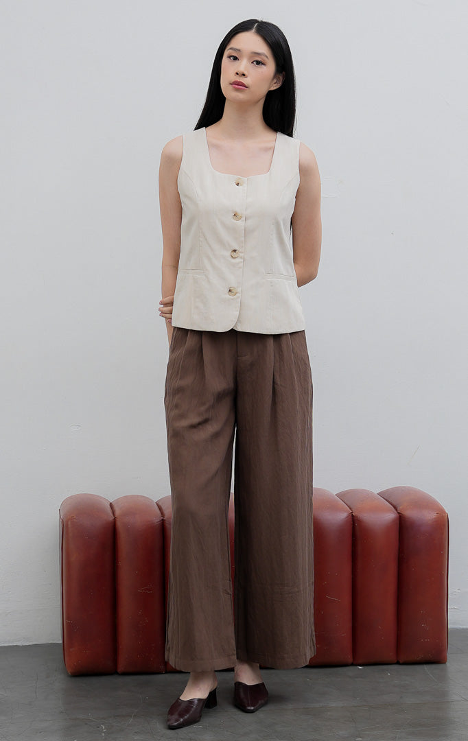 Rompi (vest) wanita tanpa lengan warna krem muda (ivory) Cedrica Vest dengan leher kotak (square neckline), kancing depan, dan detail aksen saku dekoratif.