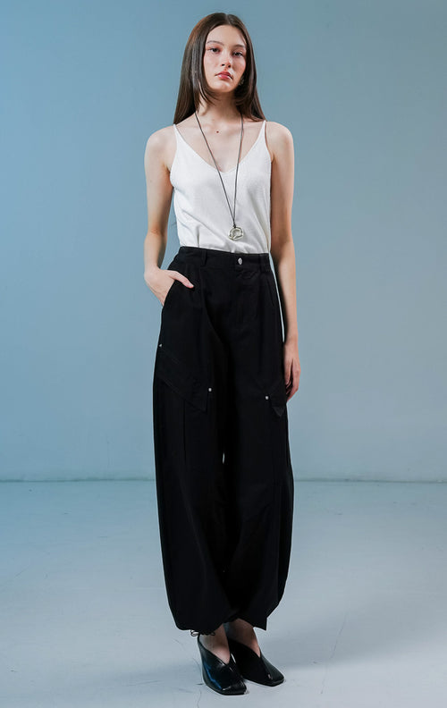 Model wanita mengenakan Lunaria Utility Straight Pants warna black, celana panjang cargo hitam wanita dengan siluet relaxed dan detail saku utilitas samping. 