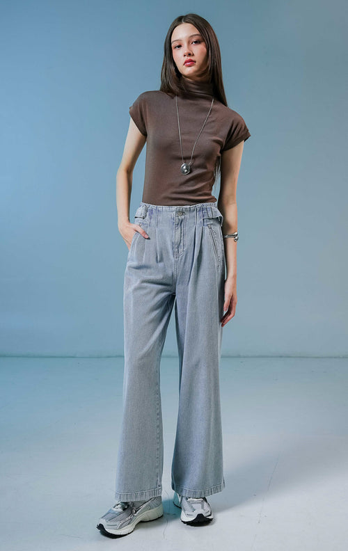 Model wanita mengenakan Luneth Pants warna light denim, celana panjang kulot jeans wanita berwarna biru muda dengan detail lipit depan dan gesper samping unik.