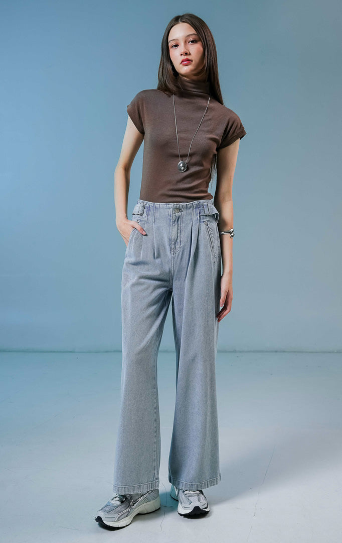 Model wanita mengenakan Luneth Pants warna light denim, celana panjang kulot jeans wanita berwarna biru muda dengan detail lipit depan dan gesper samping unik.
