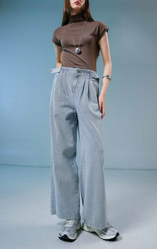 Model wanita mengenakan Luneth Pants warna light denim, celana panjang kulot jeans wanita berwarna biru muda dengan detail lipit depan dan gesper samping unik.