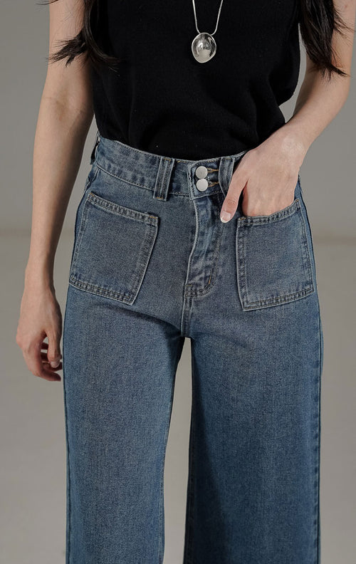 Celana jeans wanita model high waist loose fit warna biru tua dengan detail saku depan gaya retro modern.