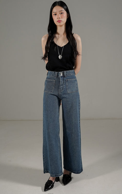 Celana jeans wanita model high waist loose fit warna biru tua dengan detail saku depan gaya retro modern.