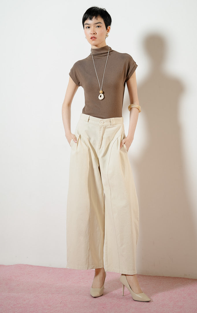 Model wanita mengenakan Regina Pants warna ivory, celana panjang kulot kerja wanita warna putih gading dengan potongan pinggang tinggi dan detail jahitan panel melengkung yang unik. 
