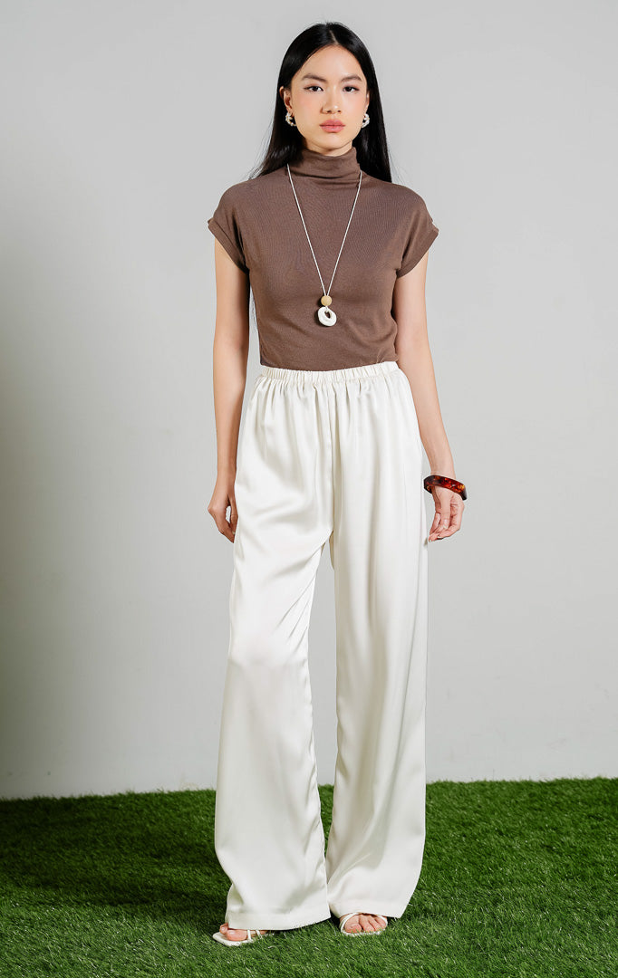Theodore Relaxed Satin Loose Pants warna ivory, celana panjang kulot wanita bahan satin mengilap dengan karet pinggang warna putih gading dari This Is April. 