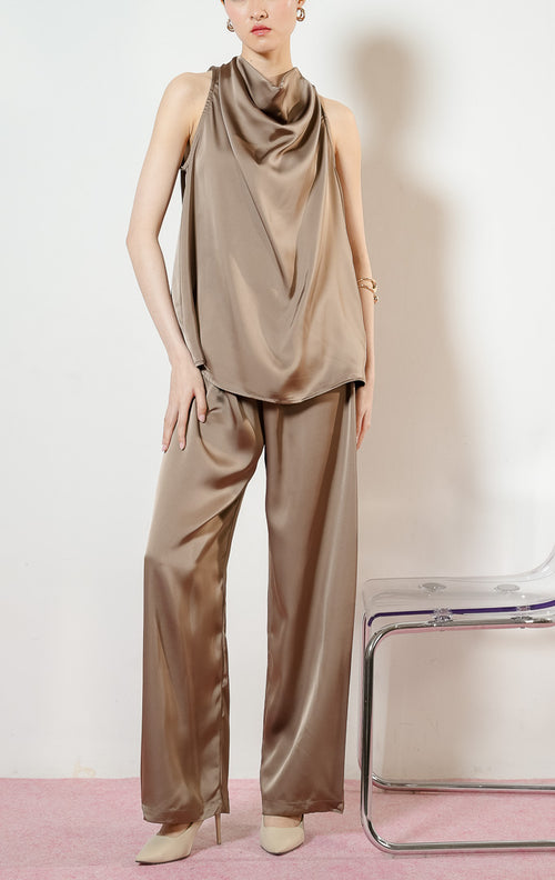 Detail bawahan model mengenakan Theodore Relaxed Satin Loose Pants warna taupe, celana panjang kulot wanita bahan satin mengkilap berwarna cokelat dengan pinggang karet. 